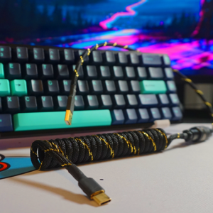 Coiled USB mechanical keyboard cable ona desk with a keyboard and computer equipment