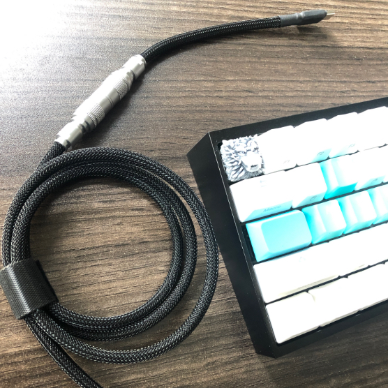 Black USB cable with keyboard on a wooden desk