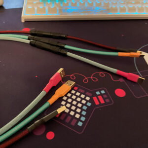 Three custom USB keyboard cables on a desk under a keyboard