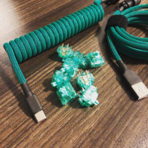 Close up of a turquoise coiled USB power cable and keyboard parts